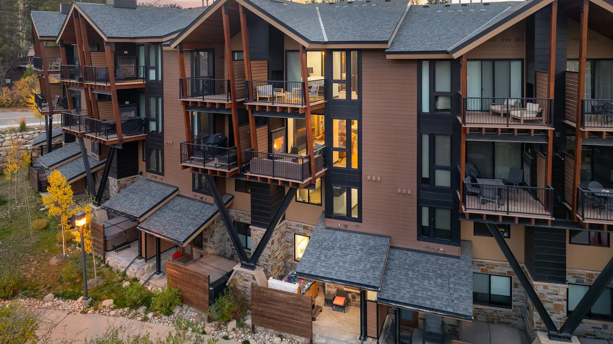 An exterior shot showcasing the modern architecture of the townhomes, multiple balconies, and landscaped outdoor gathering areas. The image communicates a sense of community and luxury, highlighting the comfortable and stylish exterior spaces available to guests.