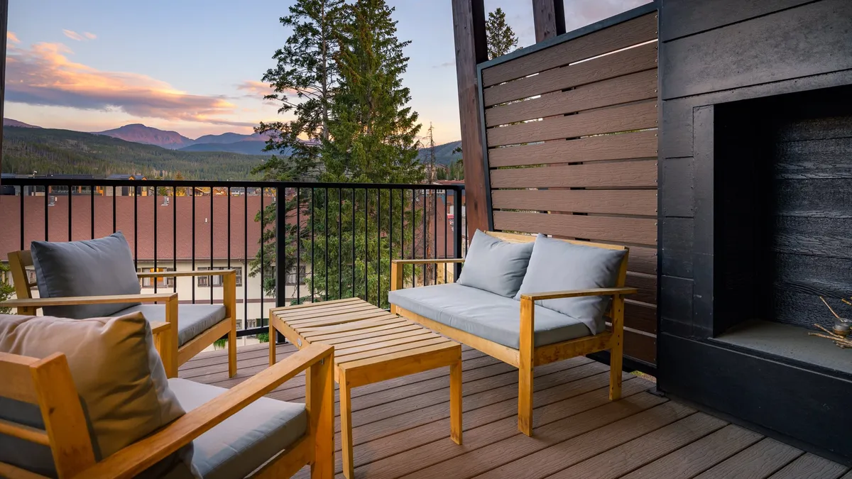 This exterior image features a cozy outdoor seating area complete with a fireplace, set against a stunning mountain backdrop. The scene conveys the tranquility of enjoying nature with the added comfort of resort-style amenities, such as the outdoor fireplace and ample seating for relaxing or socializing.