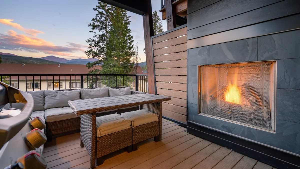 A beautiful outdoor seating area facing a stone fireplace with a view of the mountains in the background. The space features comfortable chairs and creates an intimate, warm mood for gatherings under the open sky.