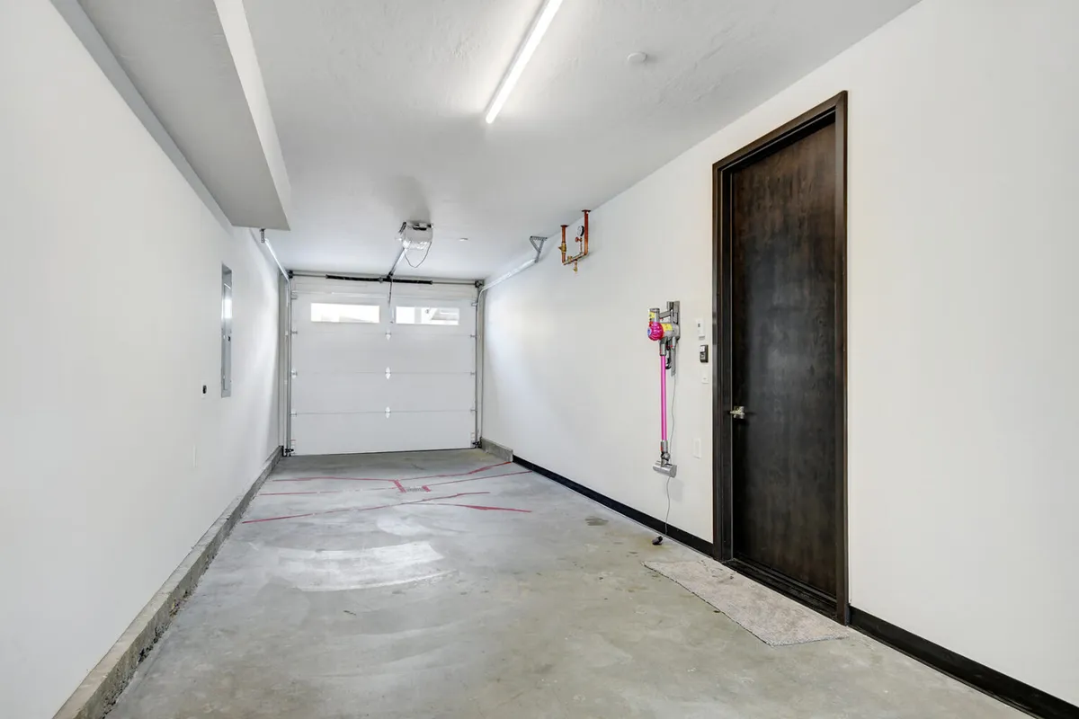 A spacious, clean, and highly organized garage with a prominent garage door, clean concrete floor, and visible storage and utility accessories. The image conveys a sense of practicality and readiness, ideal for storing bikes and outdoor equipment or parking vehicles. The uncluttered space also suggests ease of use for gear swaps before heading out on an adventure.